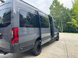 Gray custom camper van with an open side door, parked on a driveway. Ideal for your next rv rental adventure.