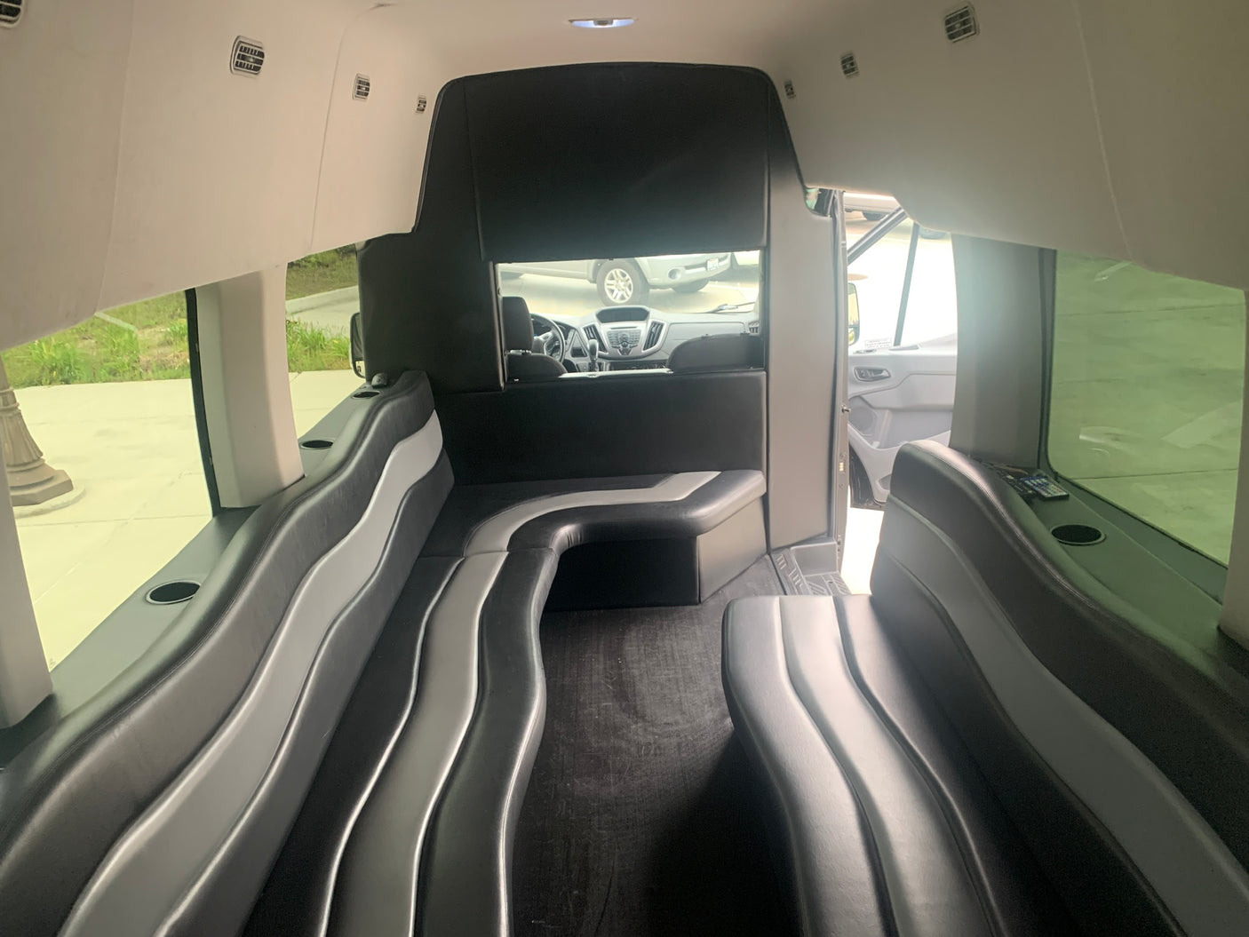 This rv rental features a custom luxury interior with continuous black and grey wavy lounge seating, extending towards the driver's cabin.