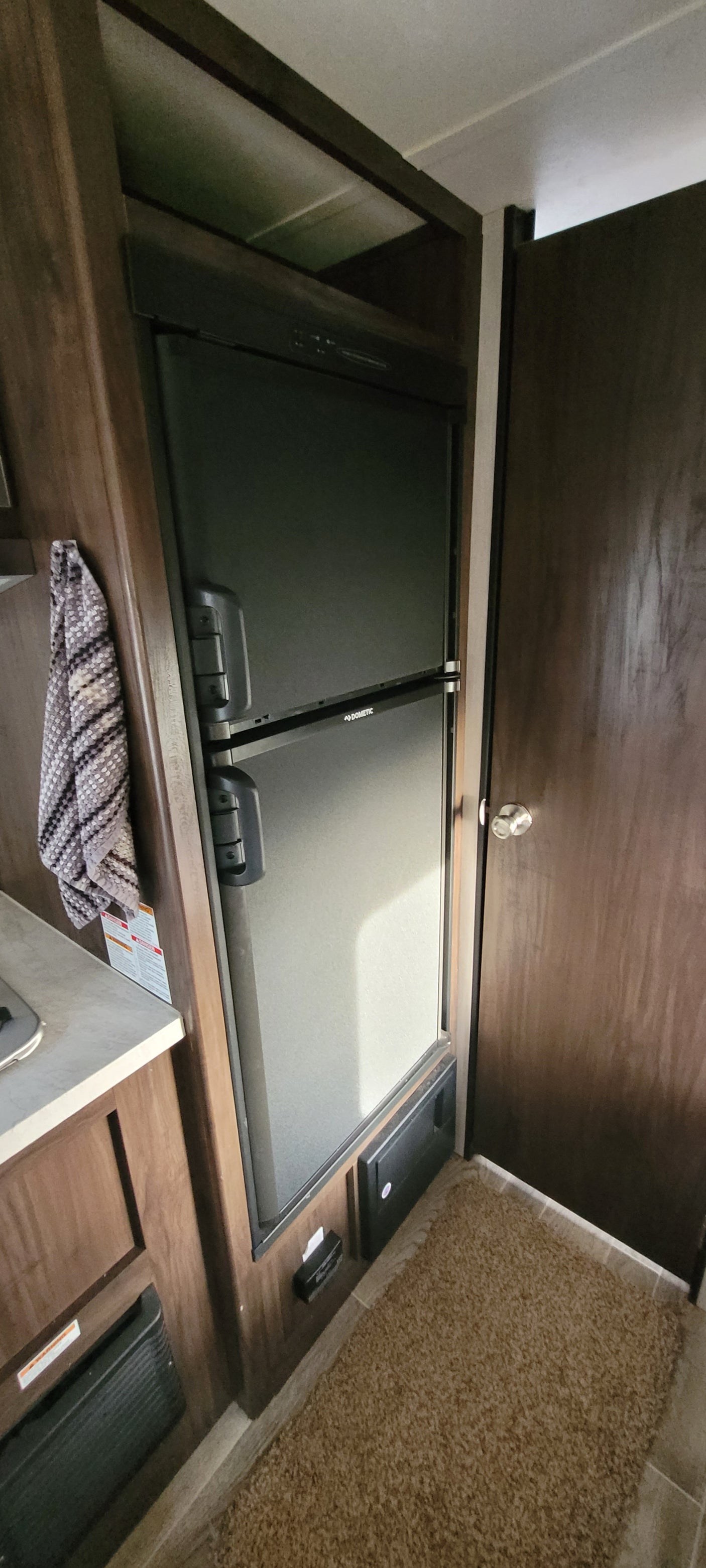Built-in Dometic refrigerator in an RV rental, with the wooden lid open revealing the interior. Ideal for road trips.