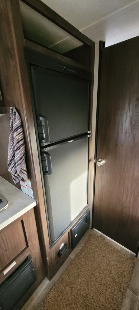 Built-in Dometic refrigerator in an RV rental, with the wooden lid open revealing the interior. Ideal for road trips.