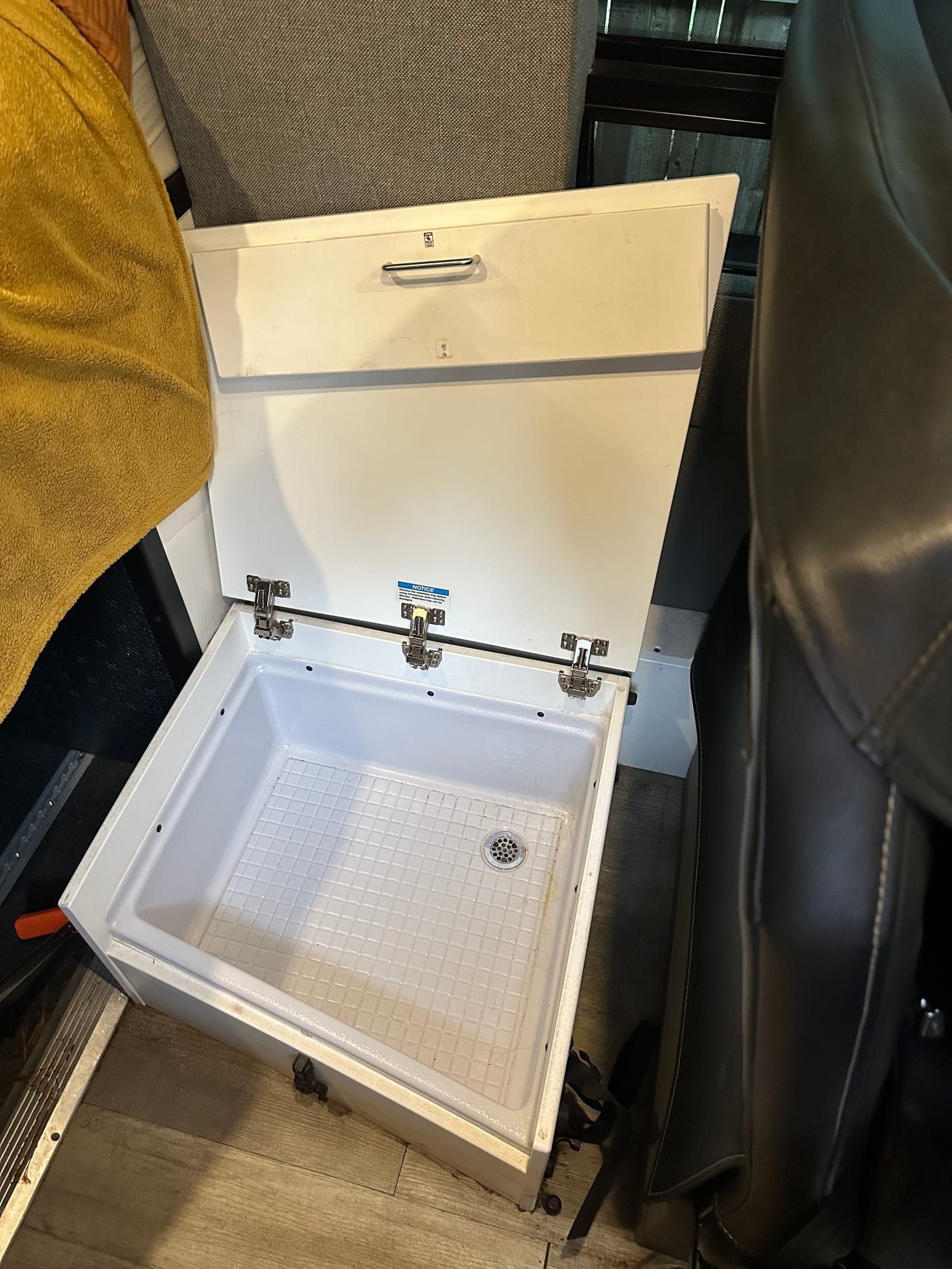 RV rental interior features a clever, compact utility sink or shower base with a drain and hinged lid for travel.
