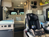 Family-friendly RV rental interior with kitchenette, seating, and child car seats for comfortable road trips.