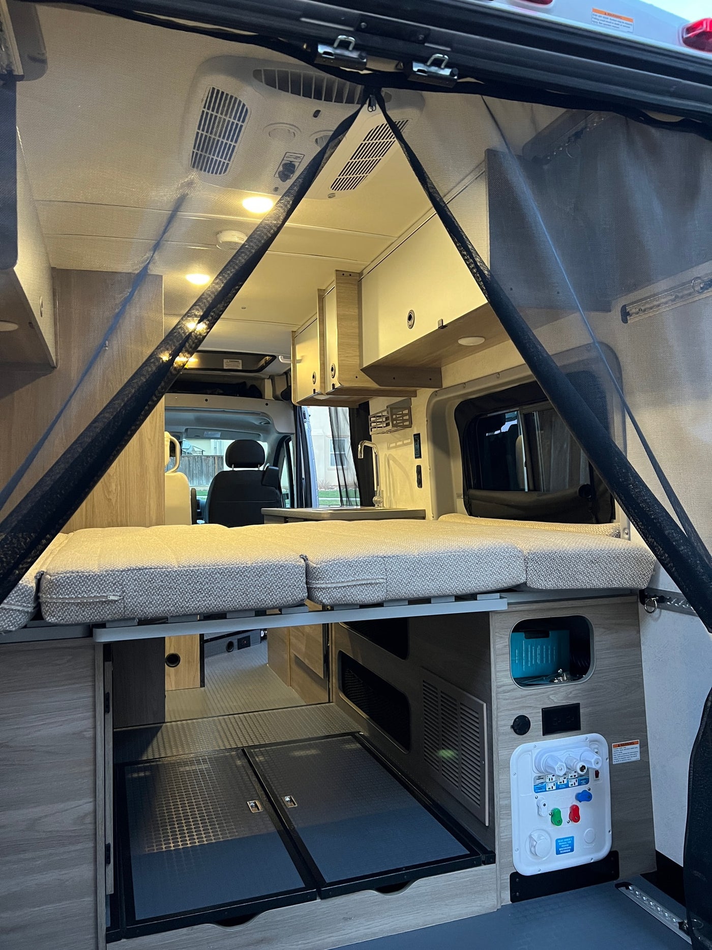 RV rental interior: A compact camper van with a rear bed, kitchen, ample storage, and a magnetic bug screen. — photo 10