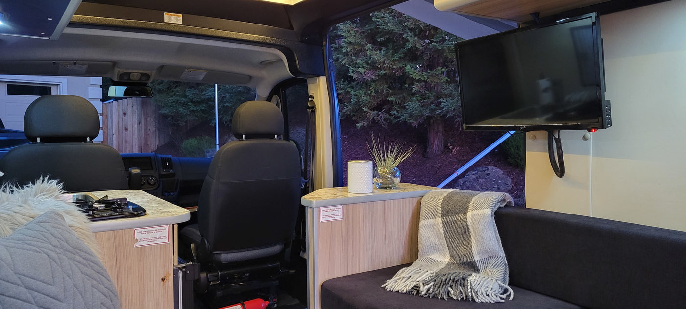 Experience an RV rental interior: front seats, kitchen area, and cozy living space with a mounted TV. — photo 6