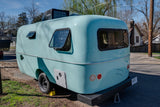 Charming light blue, vintage-style RV rental with modern AC, ideal for travel.
