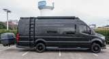 This matte black adventure RV rental, a custom Sprinter van with off-road tires and a rear cargo trailer, awaits you.