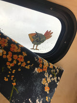 Cozy RV rental interior with a whimsical bird on the rainy window and a floral curtain.
