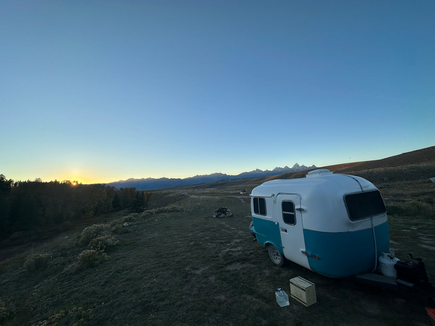 Enjoy serene camping with this unique RV rental, set against stunning mountains at sunset.