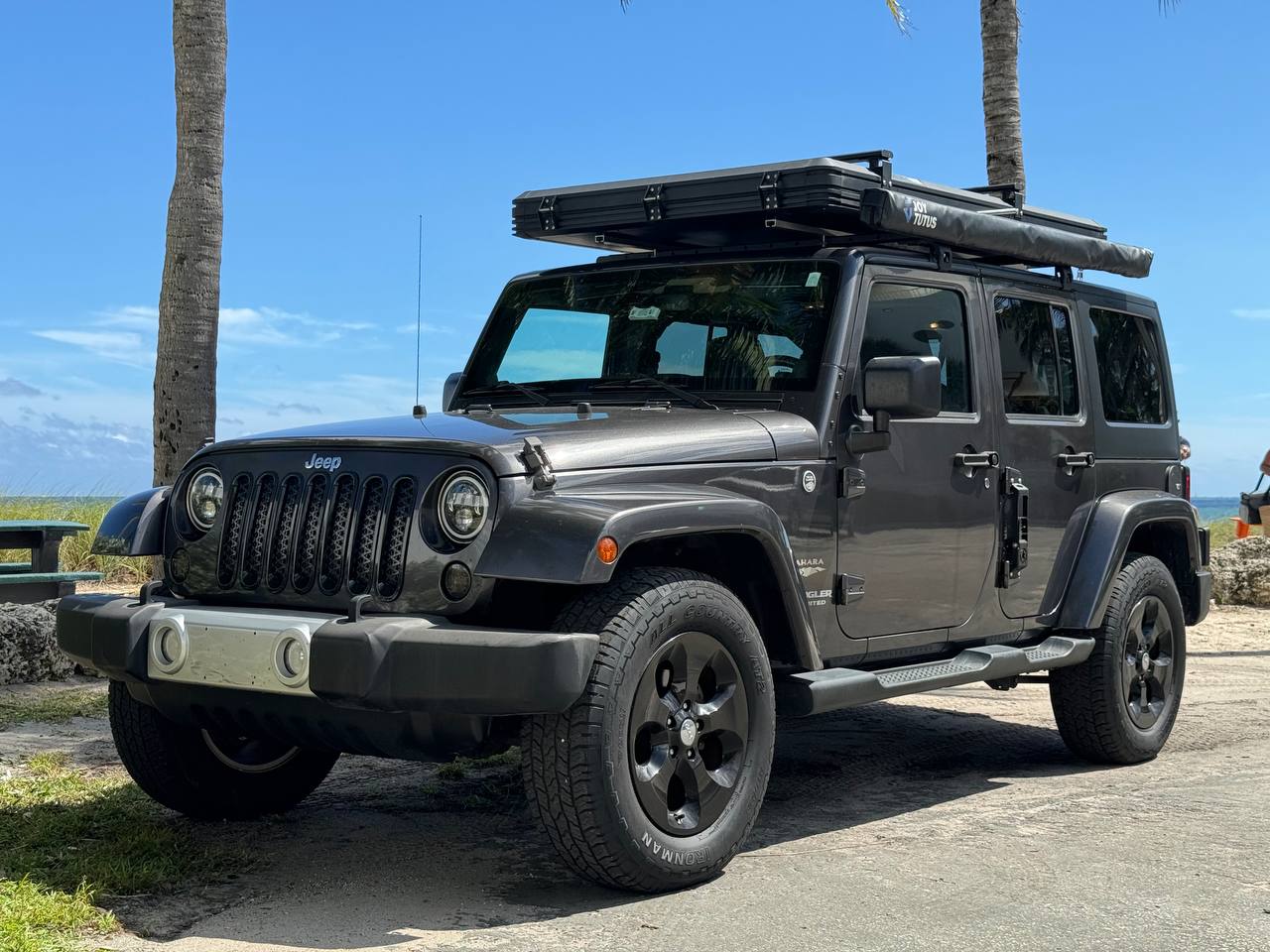 Dark gray Jeep Wrangler RV rental with rooftop tent by the beach. Ready for adventure and overland camping. — photo 2