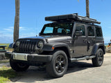 Dark gray Jeep Wrangler RV rental with rooftop tent by the beach. Ready for adventure and overland camping.