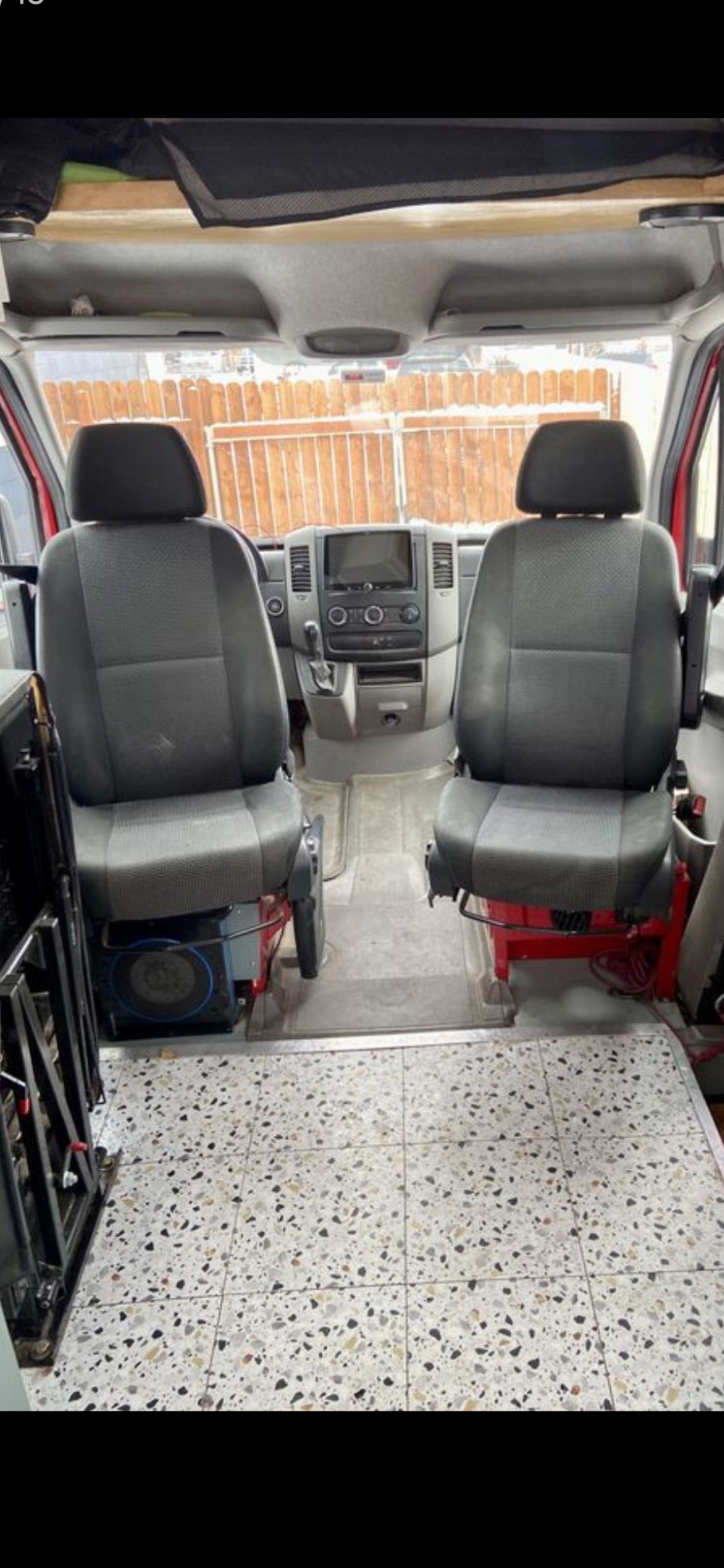 Get ready for adventure! Interior view of an RV rental van featuring front seats, a modern dashboard, and unique tiled flooring.