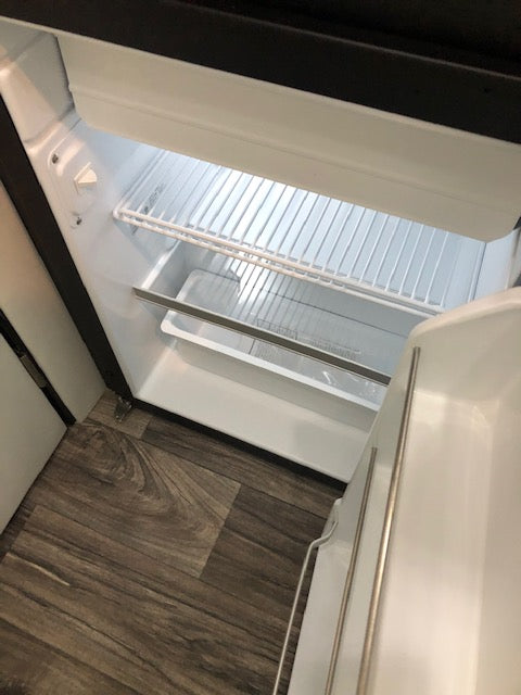View inside a clean, empty compact refrigerator in an RV rental, showing wire shelves and door compartments. — photo 15