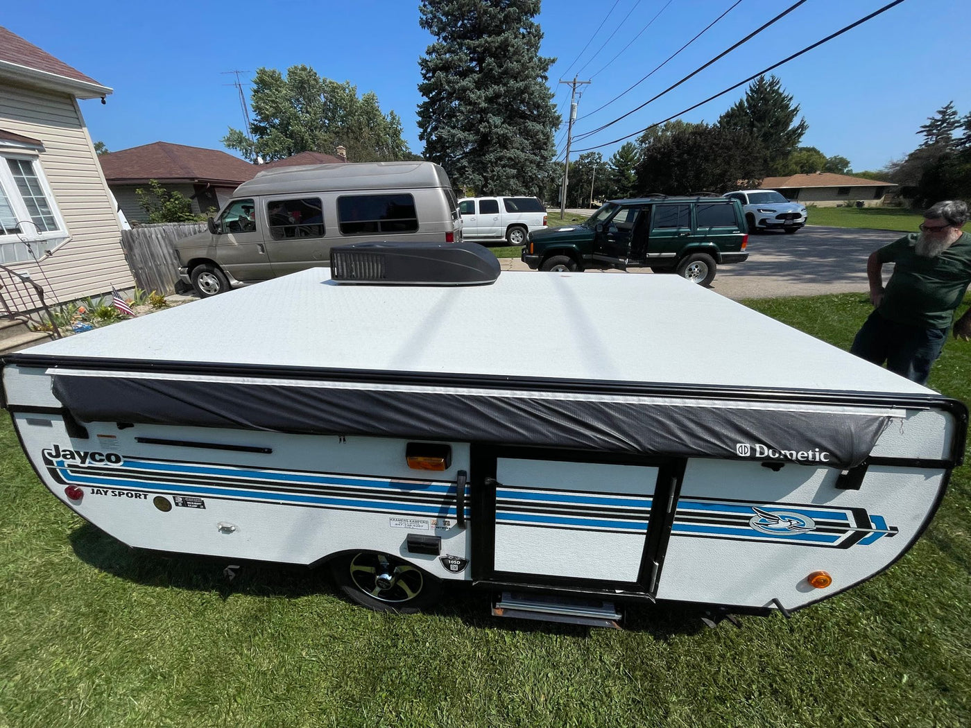 A white Jayco Jay Sport pop-up camper, with blue stripes & Dometic AC, sits on grass for RV rental. — photo 8