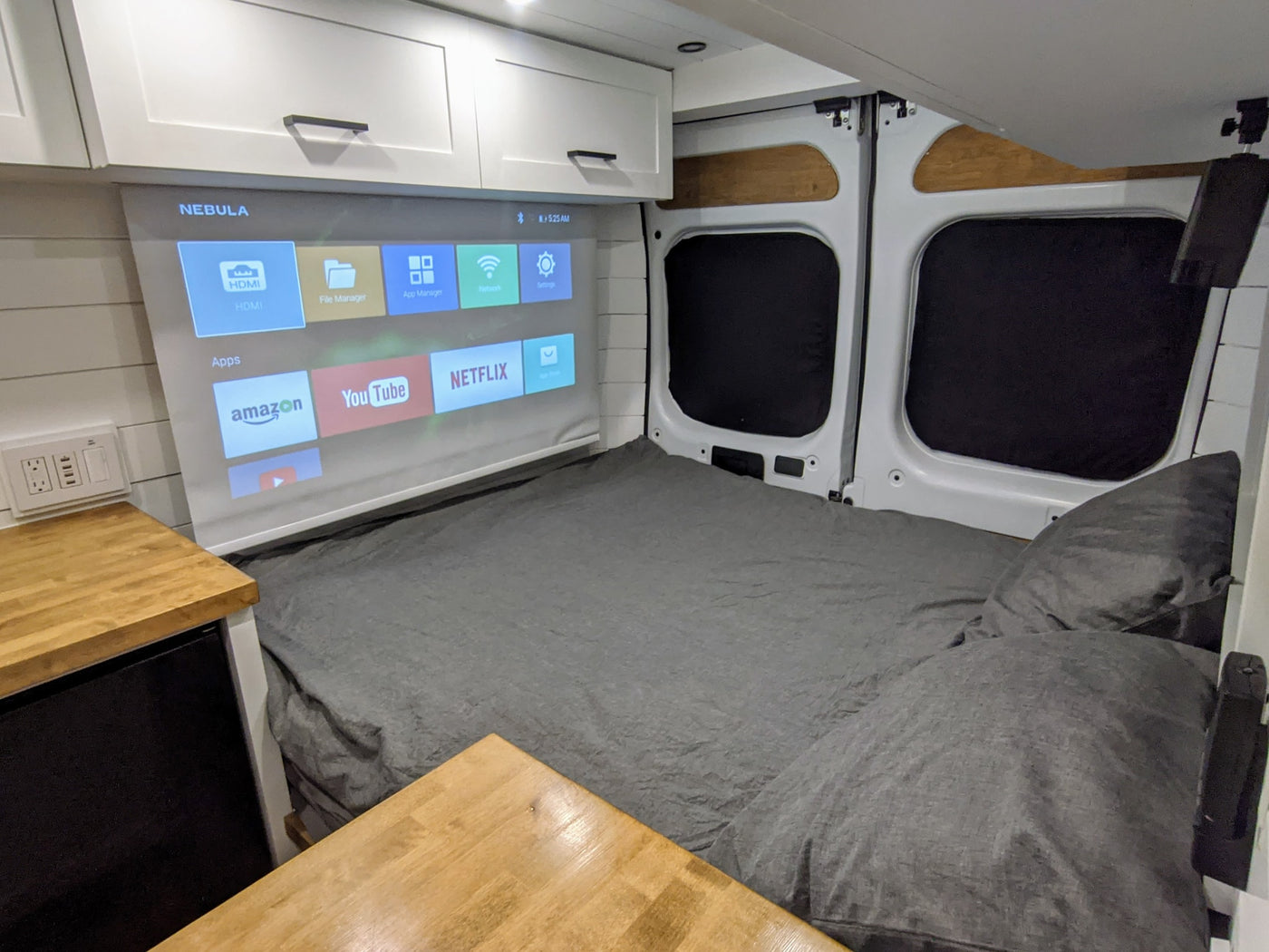 Enjoy an RV rental with a comfortable bed and built-in projector showing Nebula apps like Netflix and YouTube for ultimate entertainment. — photo 11