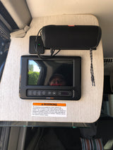 RV rental interior: BMPro control panel & JBL speaker. Safety warning. Screen reflects user & outdoors.