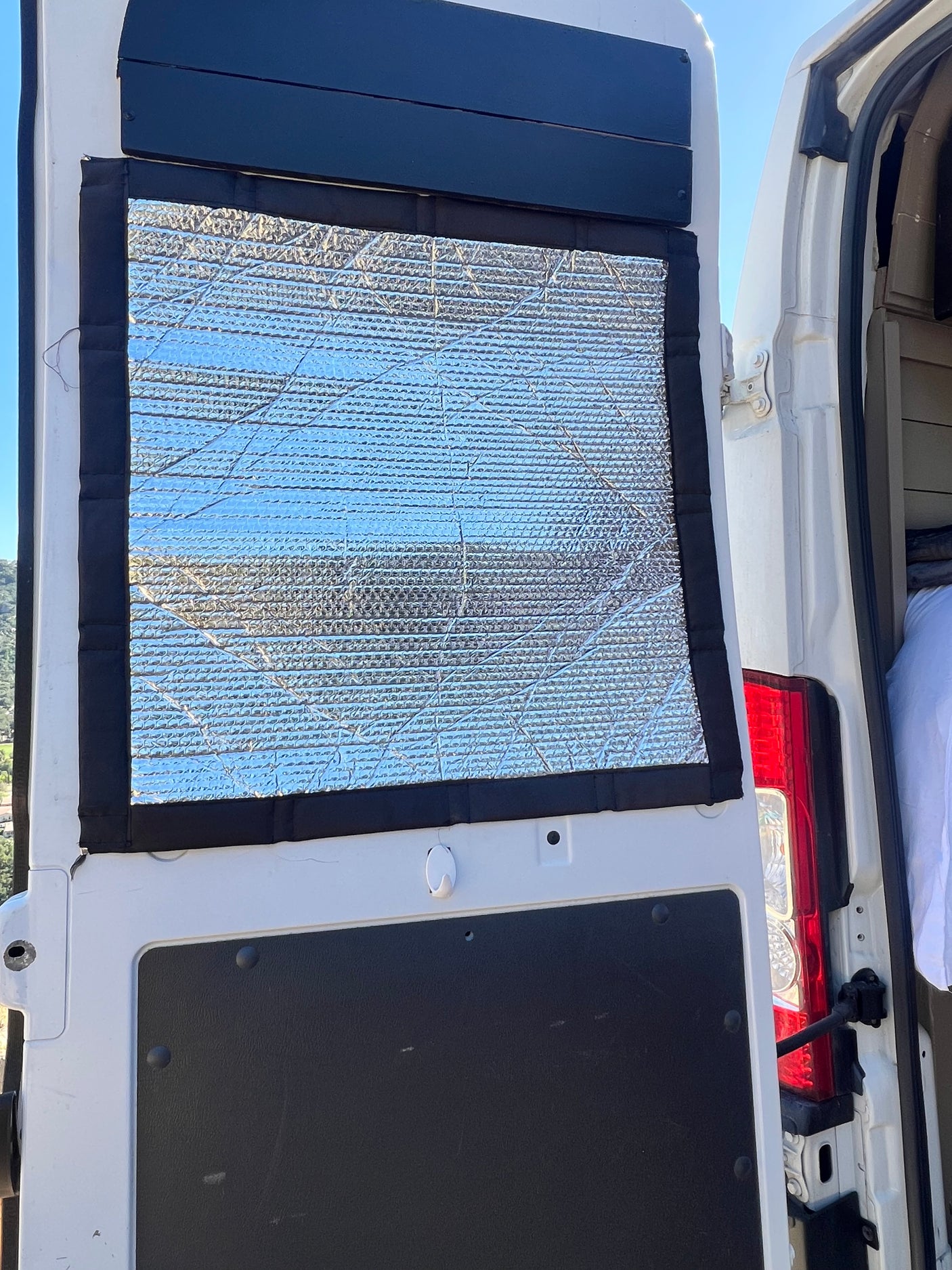 Reflective window insulation for an RV rental campervan conversion, providing privacy and temperature control for van life.