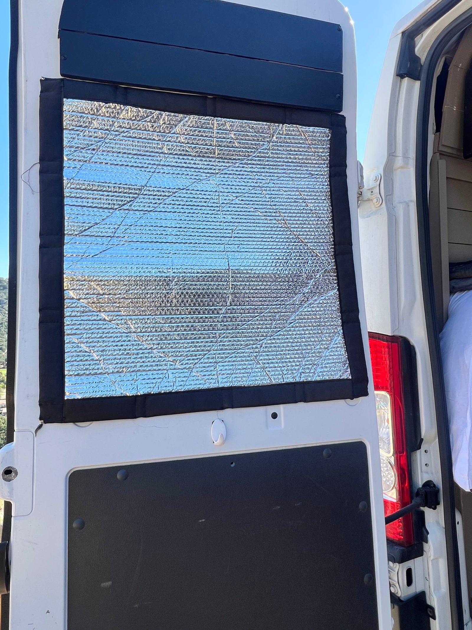 Reflective window insulation for an RV rental campervan conversion, providing privacy and temperature control for van life.