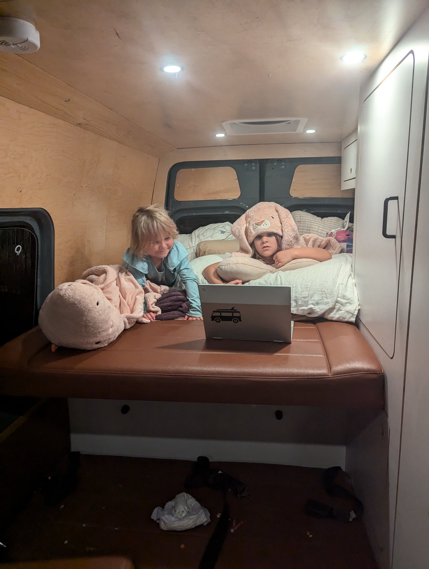 Two children in a cozy RV rental bed, one in a bunny hat, watch a laptop. Perfect for family travels. — photo 16