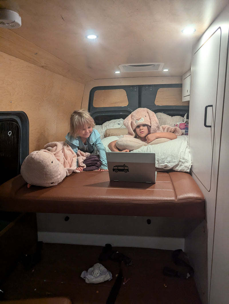 Two children in a cozy RV rental bed, one in a bunny hat, watch a laptop. Perfect for family travels. — photo 16