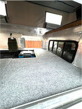 Cozy truck camper interior featuring a gray bed platform, cooler, and insulated walls. Ideal for an rv rental adventure.