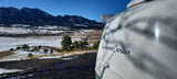 Enjoy an RV rental adventure: a Happier Camper travel trailer overlooking the snowy Boulder Flatirons.