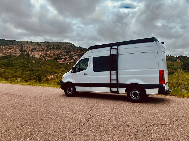 White camper van (RV rental) on a scenic mountain road under cloudy skies, perfect for adventure. — photo 5
