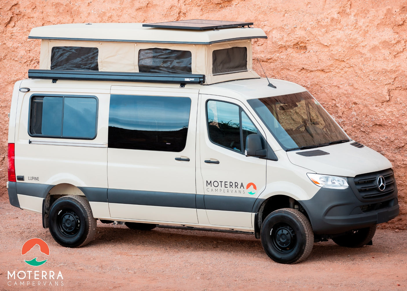Moterra's cream-colored pop-top RV rental campervan on a dirt road, ready for adventure against a red rock cliff.