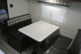 **RV rental**'s compact dinette area, featuring a white table, patterned bench seating, and window blinds.