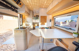 Modern RV rental interior: a bright kitchen, adjustable dining tables, and comfortable seating for your camper van trip.