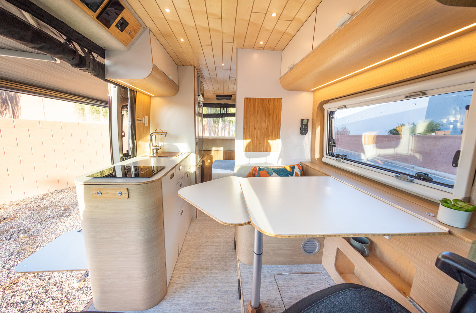 Modern RV rental interior: a bright kitchen, adjustable dining tables, and comfortable seating for your camper van trip.