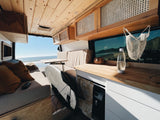 This RV rental offers a cozy campervan interior with ocean views! Features a kitchen, seating, and surfboard storage.