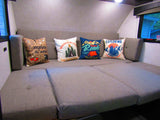 RV rental interior: A cozy gray sofa with four adventure-themed pillows, ideal for travel comfort and camping trips.