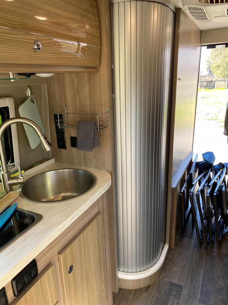  and a scenic window view.|Dark grey RV rental camper van parked on street — photo 8