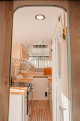 Cozy RV rental interior featuring a compact kitchen, comfortable bed, and stylish accents. Perfect for road trips!