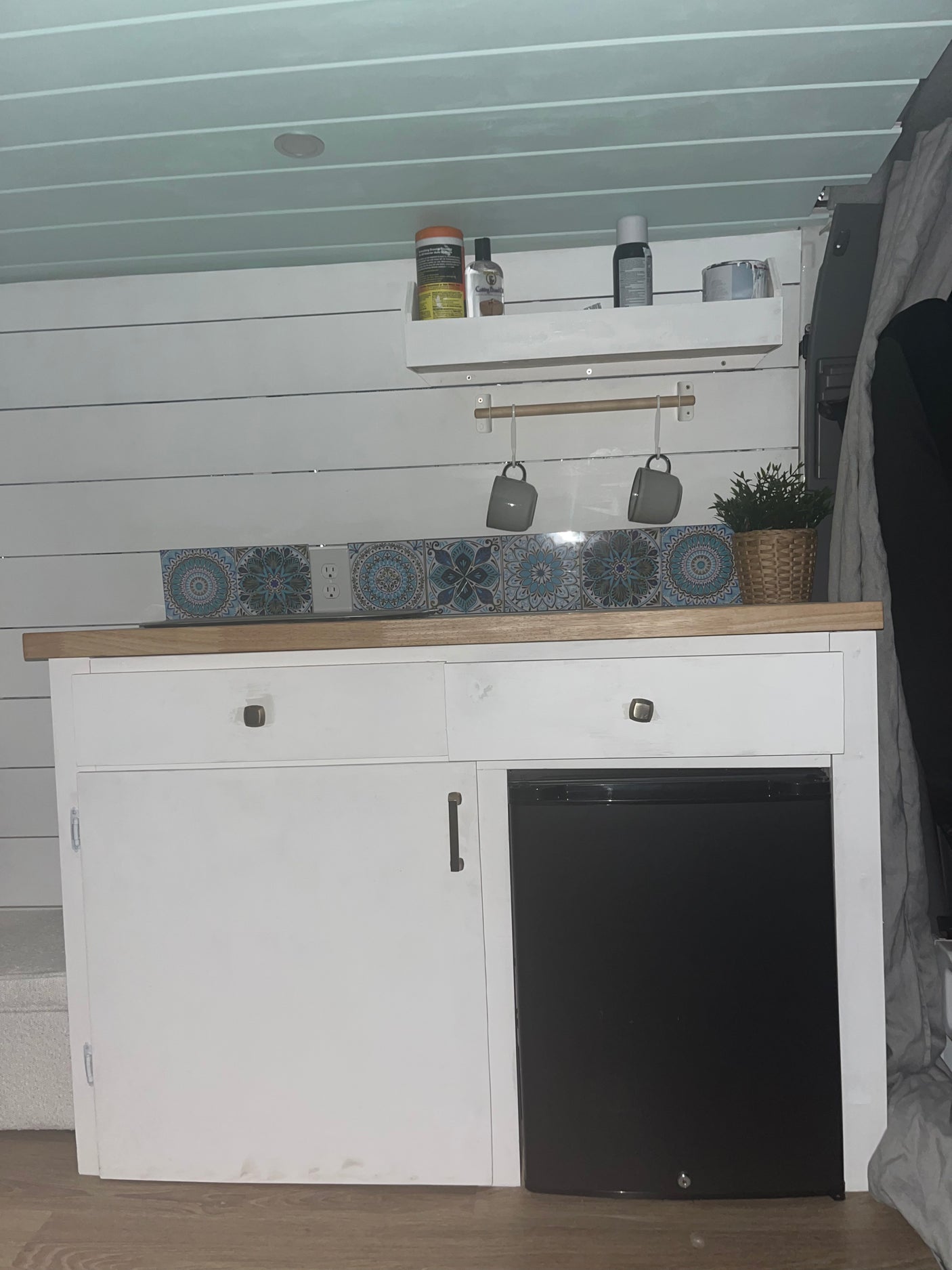 Compact RV rental kitchen featuring white cabinets, mini-fridge, and tiled backsplash, designed for small space living.