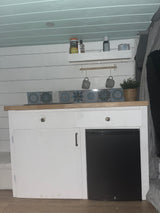 Compact RV rental kitchen featuring white cabinets, mini-fridge, and tiled backsplash, designed for small space living.
