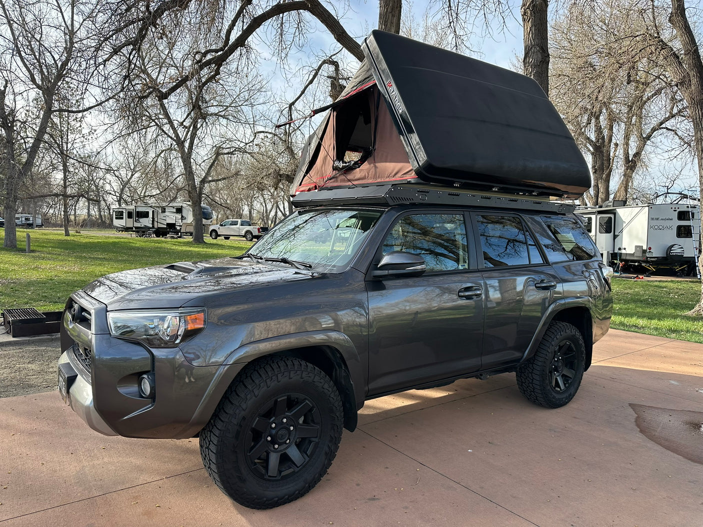 This grey SUV with a rooftop tent is ready for camping at an RV park, a unique alternative to an RV rental.