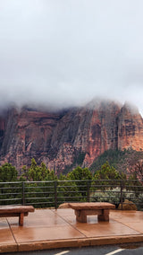 Dramatic, fog-shrouded red rock mountains at a park overlook with stone benches. Perfect for an rv rental adventure.