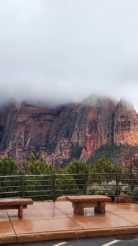 Dramatic, fog-shrouded red rock mountains at a park overlook with stone benches. Perfect for an rv rental adventure.