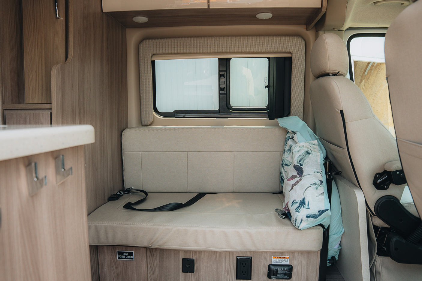 RV rental interior: Cozy dinette with bench seating, window, and power outlets for a comfortable travel experience.