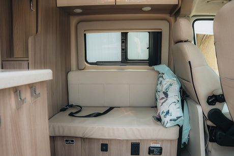 RV rental interior: Cozy dinette with bench seating, window, and power outlets for a comfortable travel experience.