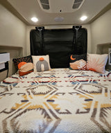 Comfortable RV rental bed with stylish desert-themed pillows & a warm, textured geometric blanket for cozy travels.