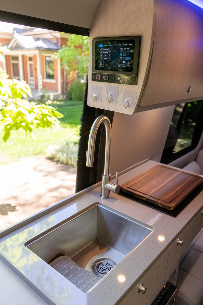 Inside a modern **rv rental**: a sleek kitchen with a stainless steel sink, wood cutting board, and a digital control panel. — photo 14