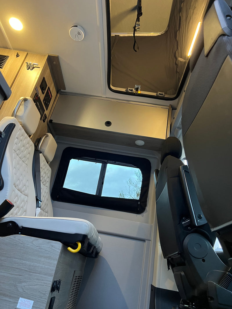 Inside an RV rental: comfortable quilted seats, overhead cabinets & lights, controls, and a roof vent providing natural light. — photo 4