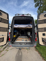 Experience van life with this RV rental: Features a raised bed, organized storage, and a sturdy pull-out platform.