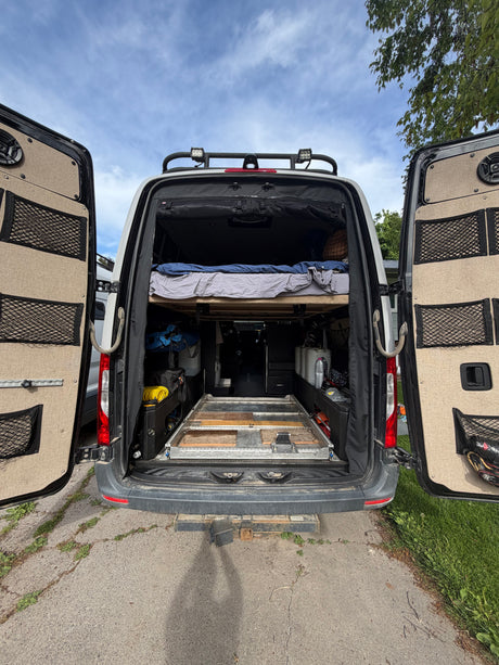Experience van life with this RV rental: Features a raised bed, organized storage, and a sturdy pull-out platform.