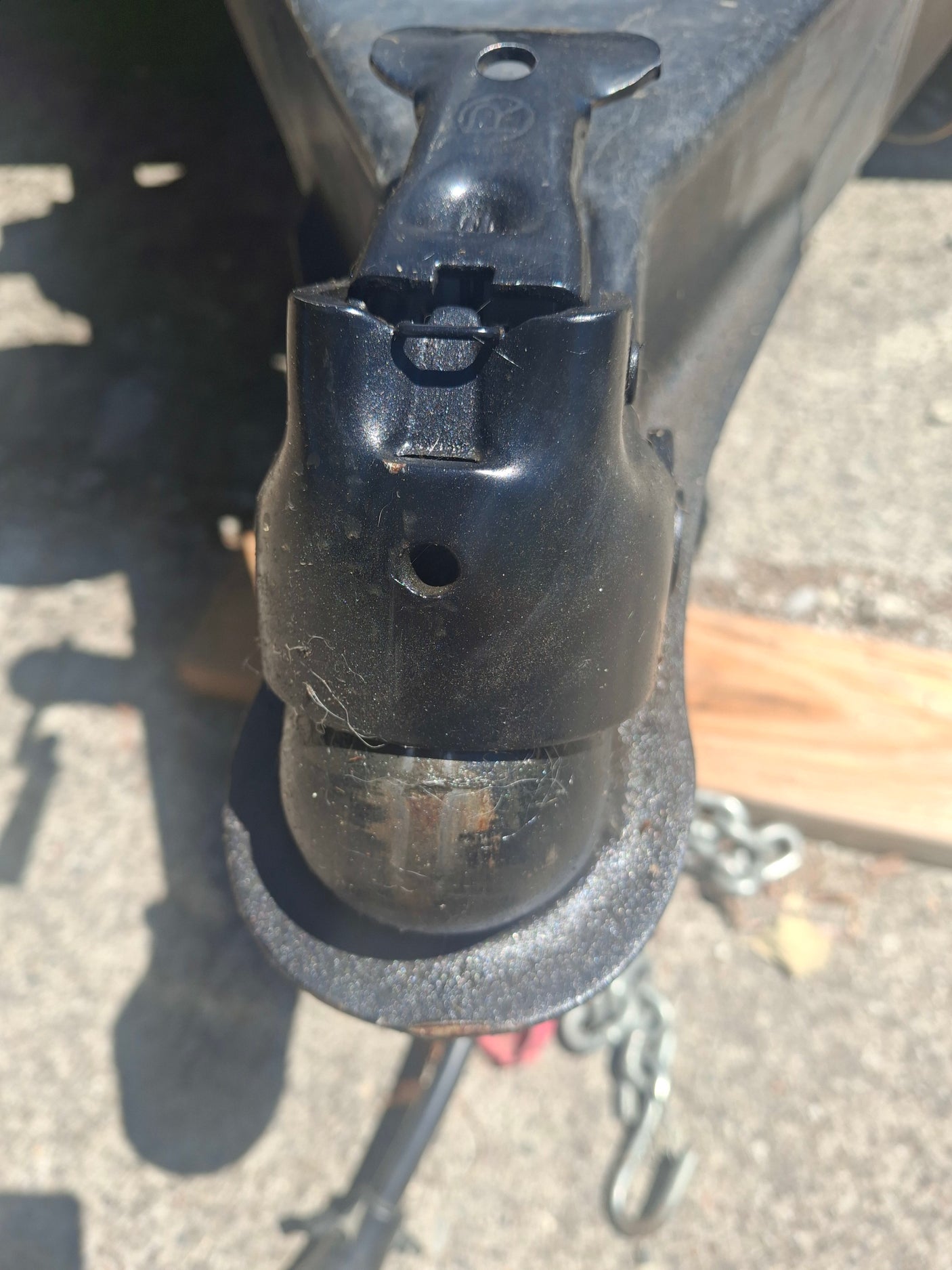 Close-up of an RV rental trailer hitch coupler securely fitted onto its ball, with safety chains nearby.
