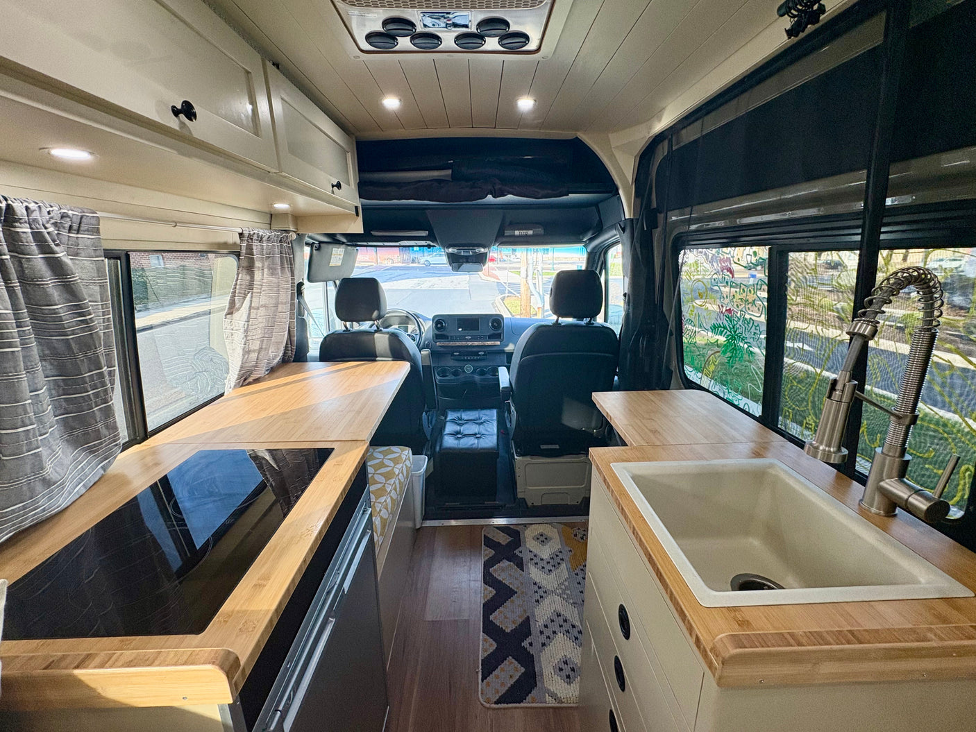Experience this rv rental interior, featuring a fully equipped galley kitchen, comfortable seating, and a cockpit view.