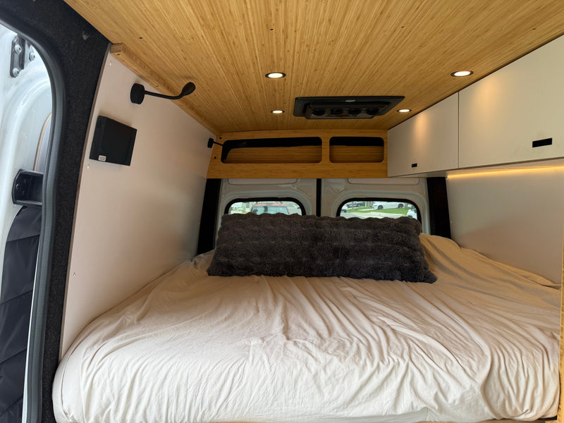 Cozy RV rental bedroom in a camper van, featuring a large bed, bamboo ceiling with lights, and integrated storage for comfortable travel. — photo 6