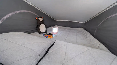 Cozy RV rental sleeping area featuring a quilted bed, stuffed bear, and reading lamp for comfort.